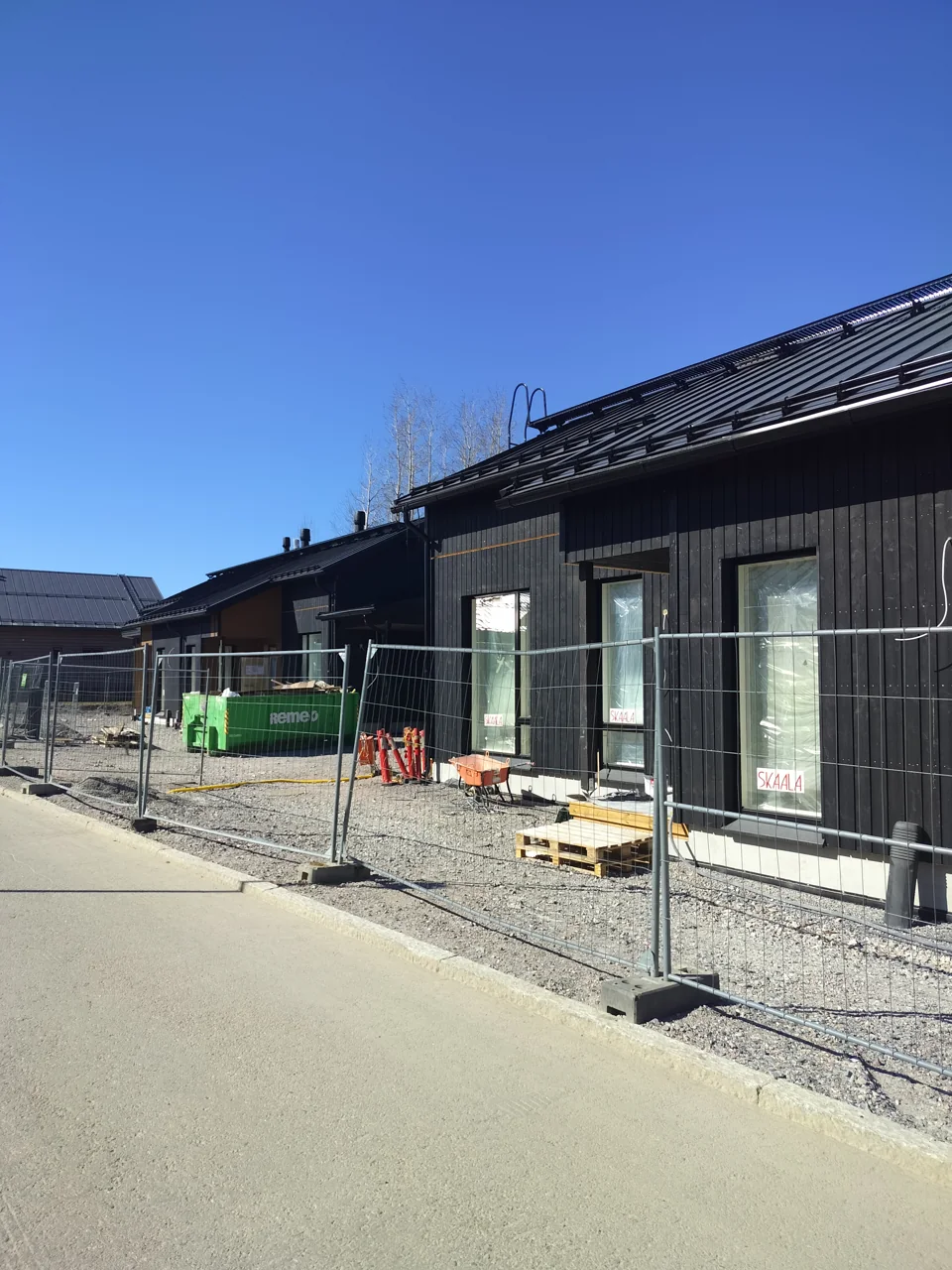 Tumma puuverhoiltu julkisivu rakennustyömaalla.
